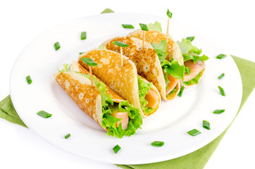 Snack rolls from pancakes, salmon and green salad leaves. 