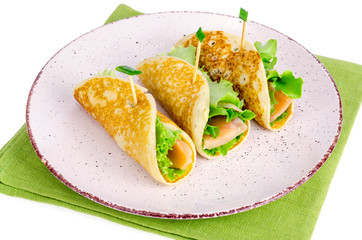 Snack rolls from pancakes, salmon and green salad leaves. 