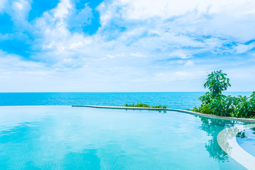 Fototapeta na wymiar Beautiful outdoor infinity swimming pool in hotel resort with sea ocean view and white cloud blue sky