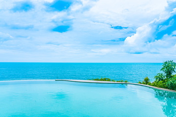 Beautiful outdoor infinity swimming pool in hotel resort with sea ocean view and white cloud blue sky