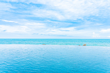 Plakat Beautiful outdoor infinity swimming pool in hotel resort with sea ocean view and white cloud blue sky