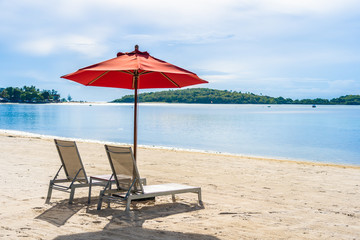 Beautiful outdoor tropical beach sea ocean with umbrella chair and lounge deck around there on white cloud blue sky