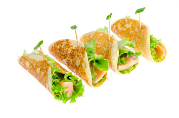 Snack rolls from pancakes, salmon and green salad leaves. 