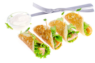 Snack rolls from pancakes, salmon and green salad leaves. 