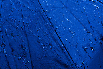 Wet blue umbrella close up image. Waterproof fabric cloth with water drops and splashes. Good or...