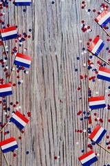 April 30 . mini flags with paper confetti lie on the edges of the wooden background. The concept of independence Day of the Netherlands and the National day of the Netherlands.Copy space.