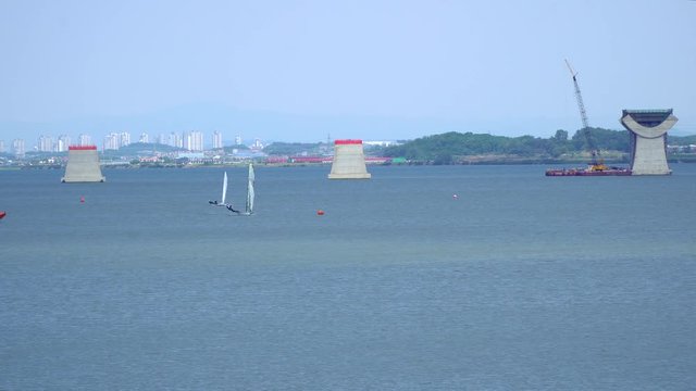 Wide angle Sailing at Asanho lake at Pyeongtaekho torist site, view on Wollangsan Mountain and bridge construction work