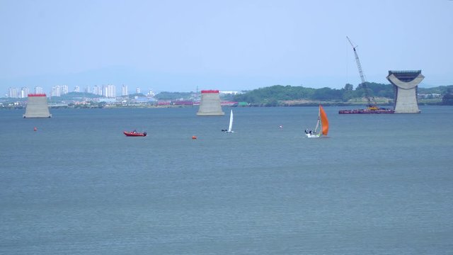 Wide angle Sailing at Asanho lake at Pyeongtaekho torist site, view on Wollangsan Mountain and bridge construction work