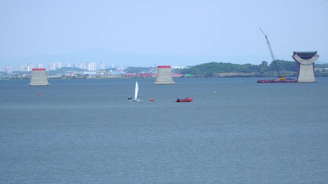 Wide angle Sailing at Asanho lake at Pyeongtaekho torist site, view on Wollangsan Mountain and bridge construction work