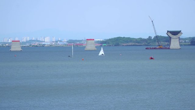 Wide angle Sailing at Asanho lake at Pyeongtaekho torist site, view on Wollangsan Mountain and bridge construction work