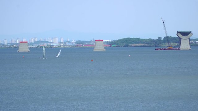 Wide angle Sailing at Asanho lake at Pyeongtaekho torist site, view on Wollangsan Mountain and bridge construction work