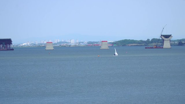 Wide angle Sailing at Asanho lake at Pyeongtaekho torist site, view on Wollangsan Mountain and bridge construction work
