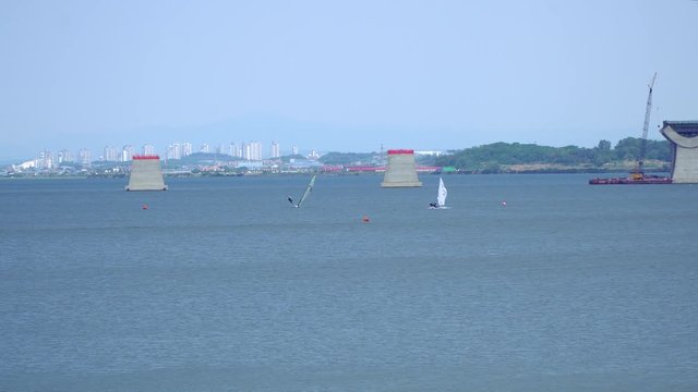 Wide angle Sailing at Asanho lake at Pyeongtaekho torist site, view on Wollangsan Mountain and bridge construction work