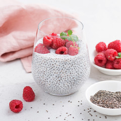 Healthy vanilla chia pudding in a glass with fresh raspberries .