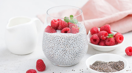 Healthy vanilla chia pudding in a glass with fresh raspberries .