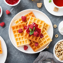 Traditional belgian waffles with fresh raspberry and jam on gray background.