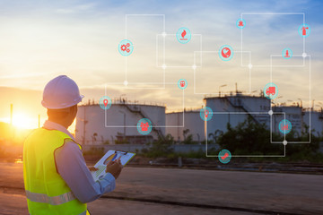 Engineer writing on the paper in front of the oil tank.Refinery, gas and oil