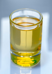 Yellow liquid in a glass cup on a white background, soft focus