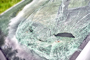 wreckage of modern car after accident broken windshield glass front detailed closeup view of damaged auto vehicle damage to window glass on driver side tech reference background photo