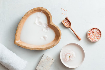 Spa setting with rice milk bowl, flowers, salt, soap and towel on white background