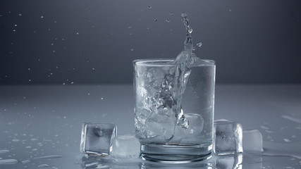 Pouring water into glass on blue background close up