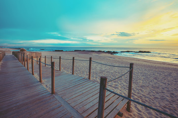 Sunset over the ocean. Wooden terrace on the sandy beach at sunset. Beautiful seashore in the evening.  Porto, Portugal, Europe