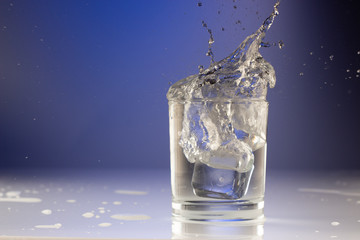 Pouring water into glass on blue background close up