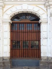 Big wooden door on white brick or concrete wall.
