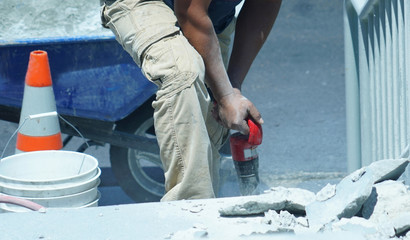 manual worker operating drill to repair the road
