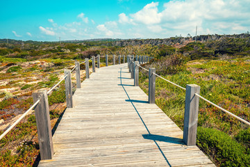 Fototapeta na wymiar The wooden stairway at the rocky seashore on a sunny day. Polvoeira the beach. Pataias, Portugal, Europe