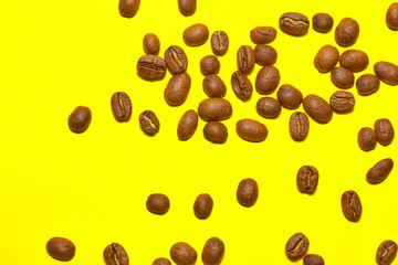 Coffee beans isolated on the yellow background. Joyful coffee-theme.
