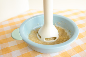 Preparing baby food, homemade.Top view of a bowl with smashed banana mixed with breast milk in a blue bowl on a tablecloth. Healthy food kids concept. Selective focus.