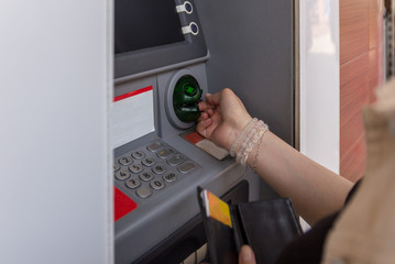 A young woman takes credit card from an ATM after withdrawing cash. Finance, withdrawal of money....