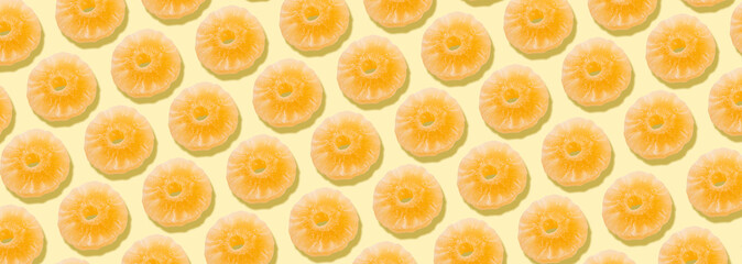 Yellow candied pineapple rings, over yellow background, panoramic image