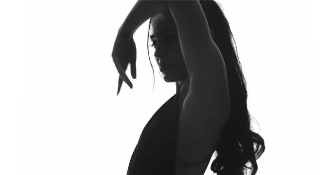 Beautiful sensual woman in body suit dancing in the studio over white wall background - black and white video in slow motion