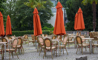Empty outdoor cafe with closed umbrellas. Street cafe with empty tables and chairs. Restaurant...