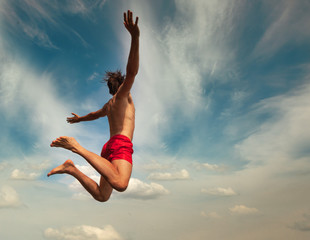 Man jumping over cloudly sky background. Summer fun lifestyle
