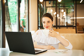 girl in cafe at lunch works behind a laptop