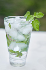 Summer hot fresh drink with mint in glass on white green grey background