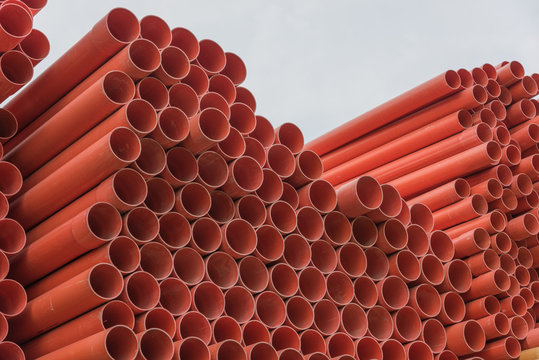 Industrial orange ppr tubes are neatly stacked, orange round tubular background material