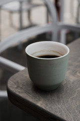 A vertical low key photo of a green cup of black coffee on a wooden table