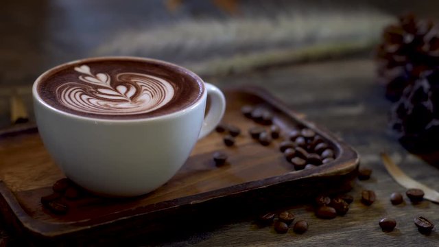 Mocha coffee with smoke and seeds on wood table, The best material for process fresh coffee. Coffee cup on interior cafe background, free space for text. Industrial food and drink background concept.