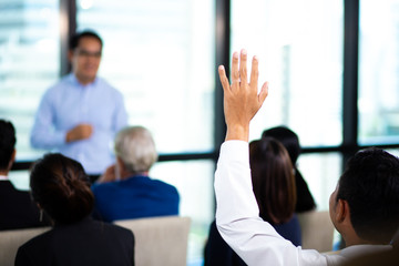 Rear view of businessman raising hand during seminar