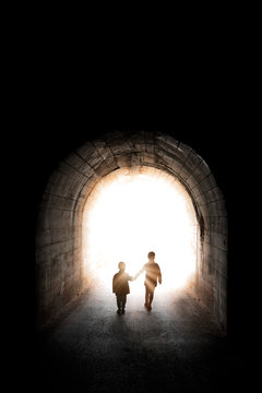 Two little siblings walking into the light