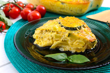 Zucchini, cheese, eggs, cream and greens casserole on a white wooden background. Portion of...