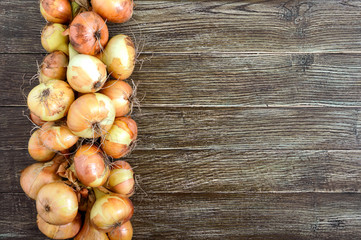 A large bunch of onions on a wooden table. Fresh harvest, popular healthy vegetables. Free space for your project. Top view, flat lay. Food background.