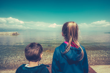 Little children standing on the lake shore