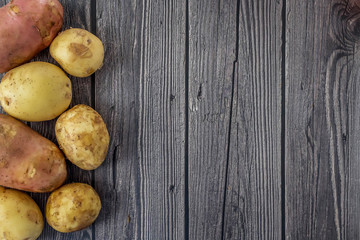 Young raw unpeeled potatoes on wooden dark background. Harvest. Flat lay composition. Layout with copy space for text .