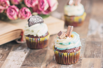 Handmade chocolate muffins with decorations. Book and a bouquet of roses