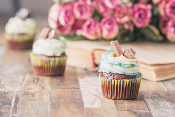 Handmade chocolate muffins with decorations. Book and a bouquet of roses